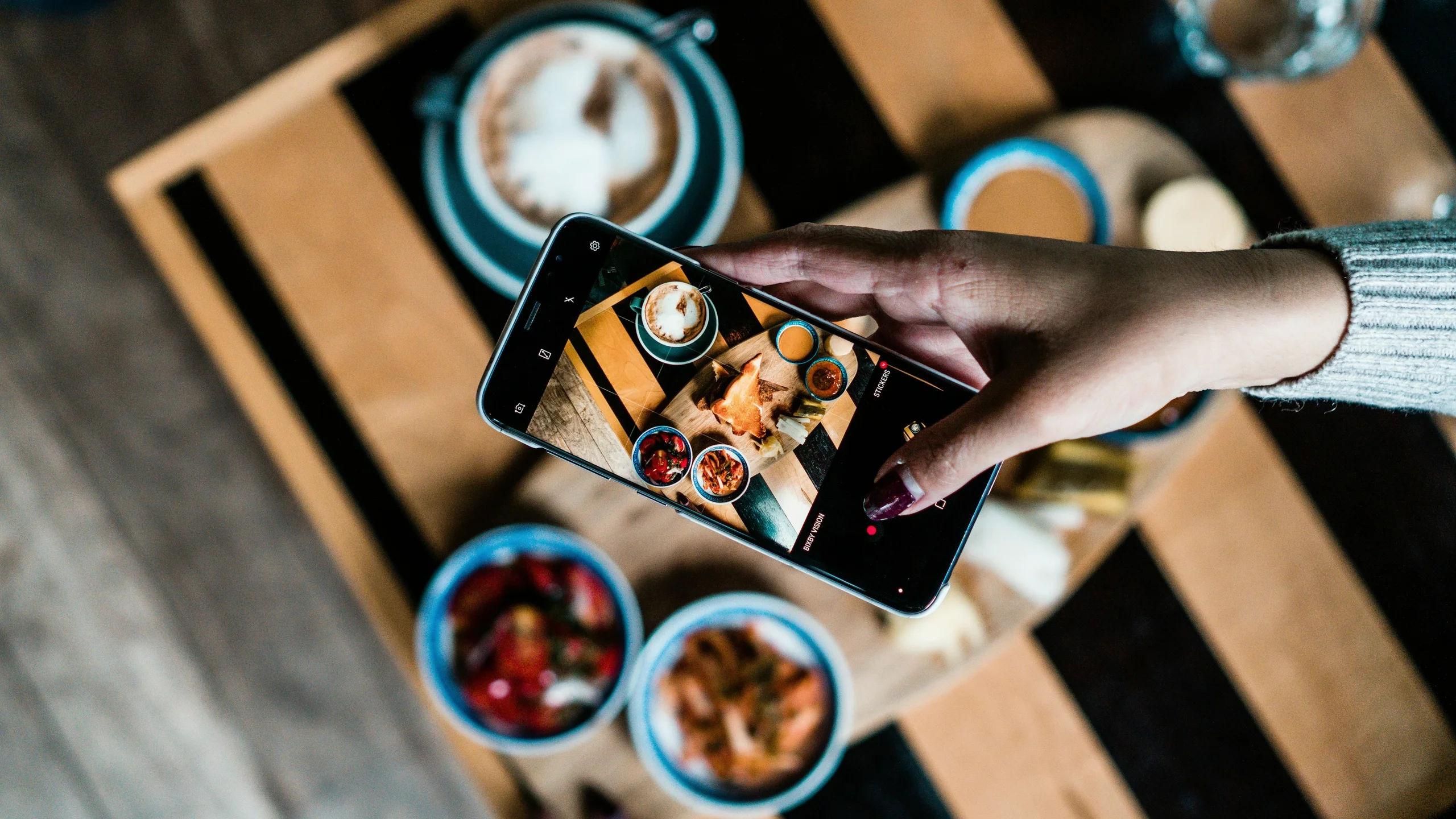 A hand photographing a brunch with a phone: UX redesign of a food content platform