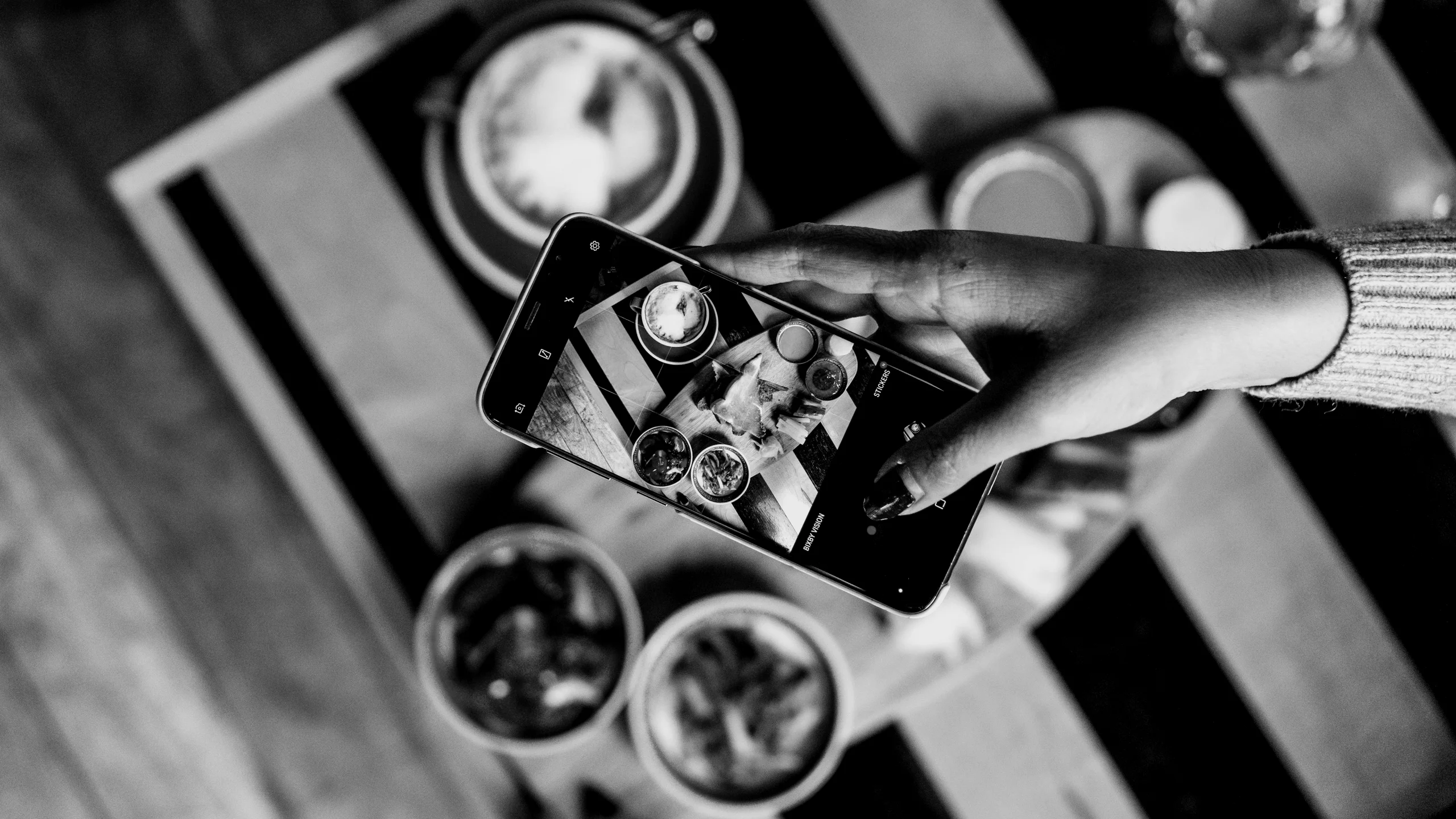A hand photographing a brunch with a phone, in black and white: UX redesign of a food content platform